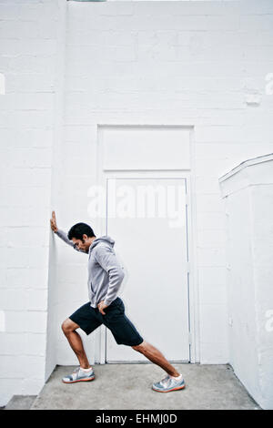 Mixed race man stretching in doorway Stock Photo