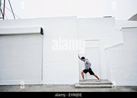 Mixed race man stretching in doorway Stock Photo