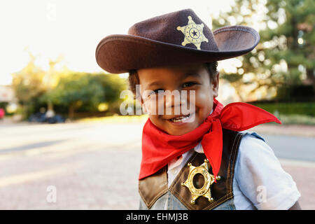 Mixed race boy in cowboy costume smiling outdoors Stock Photo