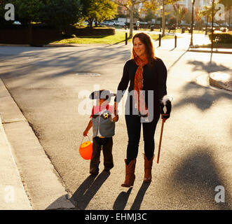 Mother and son dressed as cowboy crossing street Stock Photo