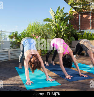 Women practicing yoga together on urban rooftop Stock Photo