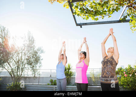 Women practicing yoga together on urban rooftop Stock Photo