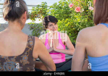 Teacher working with yoga students outdoors Stock Photo