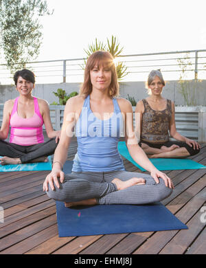 Women sitting on yoga mats on rooftop Stock Photo