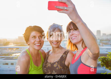 Women taking cell phone selfie on urban rooftop Stock Photo