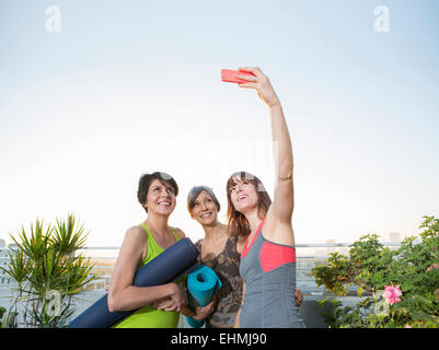 Women taking cell phone selfie on urban rooftop Stock Photo