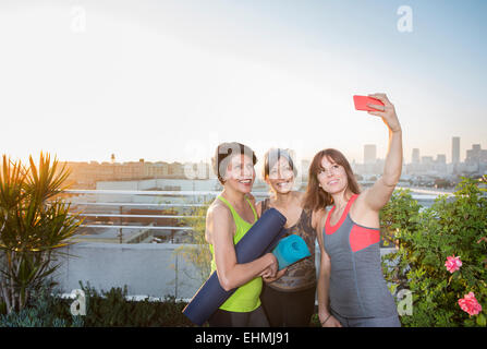 Women taking cell phone selfie on urban rooftop Stock Photo