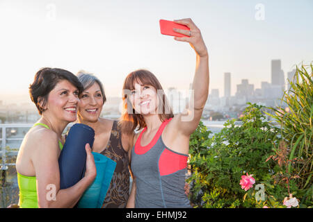 Women taking cell phone selfie on urban rooftop Stock Photo