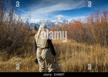 Older Caucasian woman carrying fishing supplies in field Stock Photo