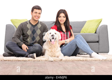 Young couple sitting on the floor with a dog isolated on white background Stock Photo