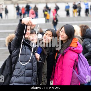 Group of Japanese tourists, girls posing for a selfie in Trafalgar Square, London Stock Photo