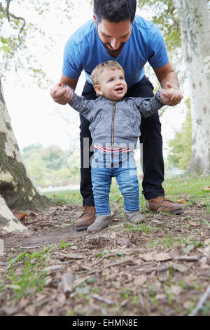 Caucasian father helping baby son walk outdoors Stock Photo