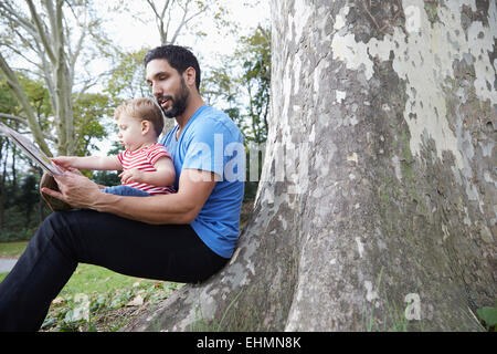 Caucasian father and baby son using digital tablet outdoors Stock Photo