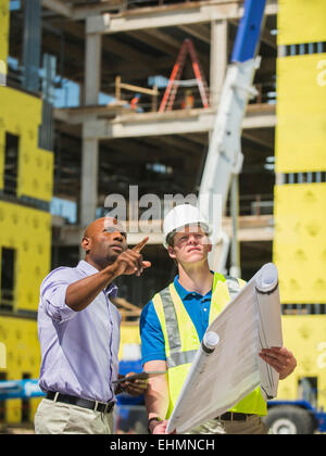 Businessman and construction worker reading blueprints at construction site Stock Photo