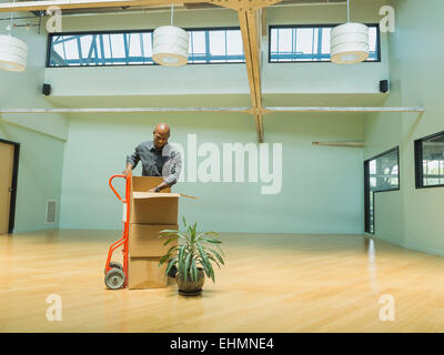 Black businessman unpacking cardboard boxes in empty office Stock Photo