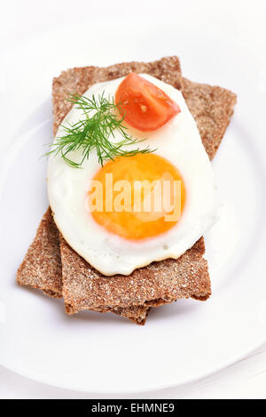 Fried egg, dill and tomato slice on crispbread, top view Stock Photo