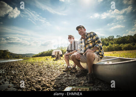 Caucasian father and son sitting in canoe on riverbed Stock Photo