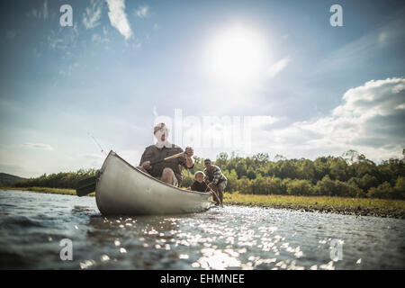 Three generations of Caucasian men paddling canoe in river Stock Photo
