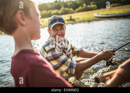 Caucasian father and son fishing in river Stock Photo