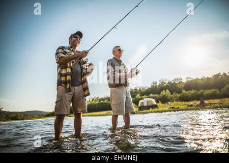 Caucasian father and son fishing in river Stock Photo