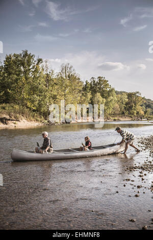 Three generations of Caucasian men in canoe on river Stock Photo
