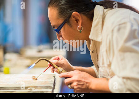 Close up of Native American jeweler using blowtorch in studio Stock Photo