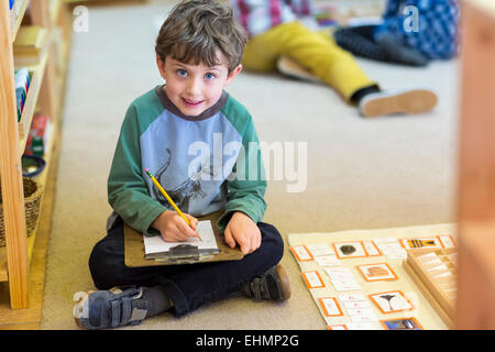 Smiling boy writing in classroom Stock Photo