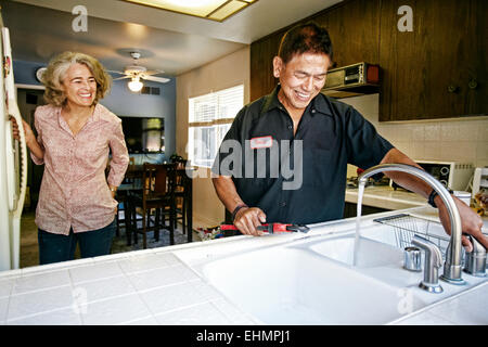 Plumber testing sink for woman in kitchen Stock Photo