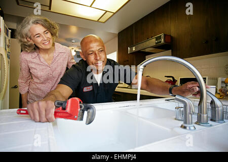 Plumber testing sink for woman in kitchen Stock Photo