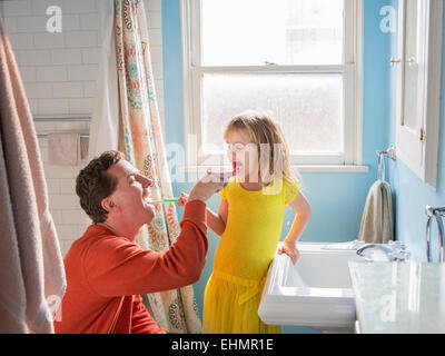 Caucasian father and daughter brushing teeth in bathroom Stock Photo