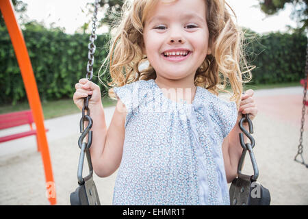 Caucasian girl playing on swing Stock Photo