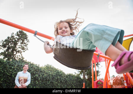 Caucasian father pushing daughter on swing