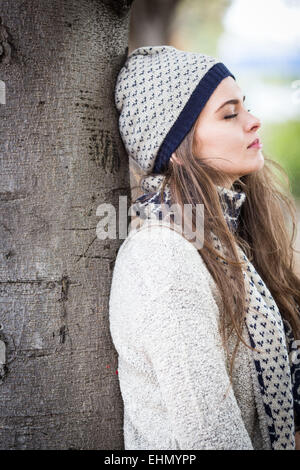 Woman leaning against a tree. Stock Photo