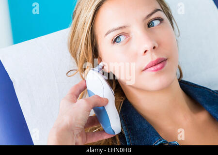 Checking the temperature of a patient with tympanic thermometer. Stock Photo