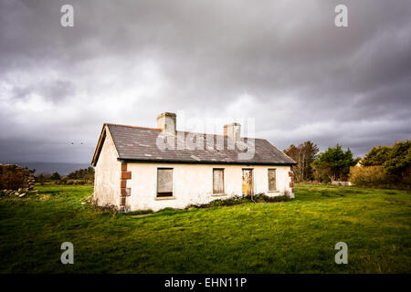 Ruined abandoned rural house with windows boarded up in the West of Ireland Stock Photo