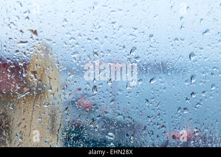 Blue rainy background, flowing down water drops on the window glass Stock Photo