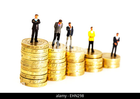 pay scale within business represented by pound coin stacks and businessmen isolated cut out cutout white background Stock Photo