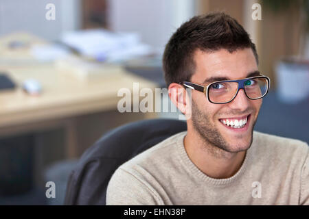 Portrait of a smart an handsome young man in office with available light Stock Photo