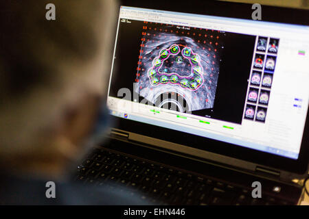 Prostate cancer radiotherapy surgery. Radiologist inserting a hollow needle through a template grid (black square) and through a patient's perineal skin, during a treatment for prostate cancer. Montsouris institut, Paris, France. Stock Photo