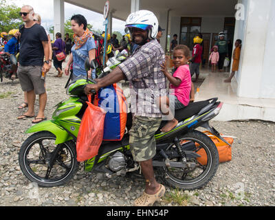 Dekai, Indonesia - January 12, 2015: A man with a child sitting on a motorcycle in front of a local airport Stock Photo