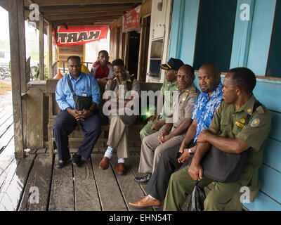 Dekai, Indonesia - January 12, 2015: Local Police officers wearing uniforms and civilian men sitting and resting in front of a b Stock Photo