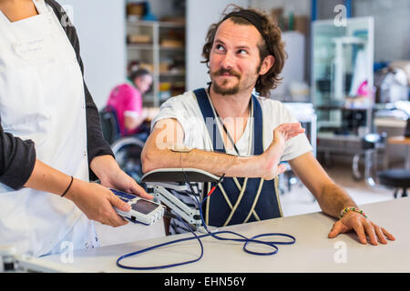 Hemiplegic patient after a stroke, and occupational therapist during an electrostimulation session, Department of Physical Medicine and Rehabilitation Hospital of Bordeaux hospital, France. Stock Photo