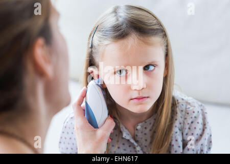 Checking the temperature of a 4 year old girl with ear thermometer. Stock Photo