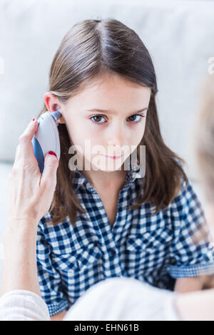 Checking the temperature of a 7 year old girl with ear thermometer. Stock Photo