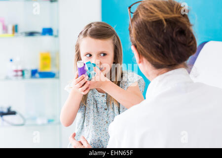 Doctor instructing a girl on how to use an asthma inhaler. Stock Photo