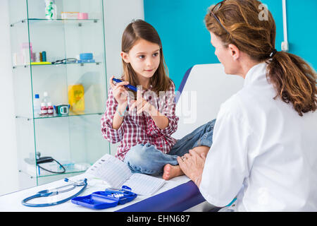 Diabetic 7-year- old girl listening to her doctor explain how to use a type of insulin syringe. Stock Photo