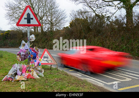 Sports car speeding past a roadside shrine, the scene of a fatal accident Stock Photo