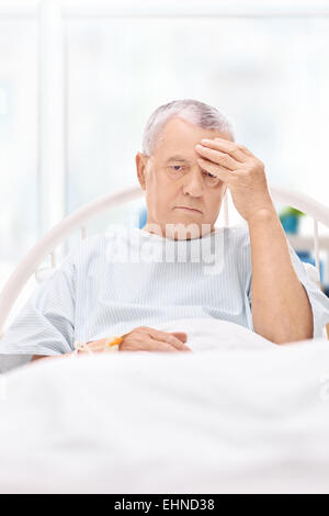 Mature patient having a headache and lying in a bed Stock Photo