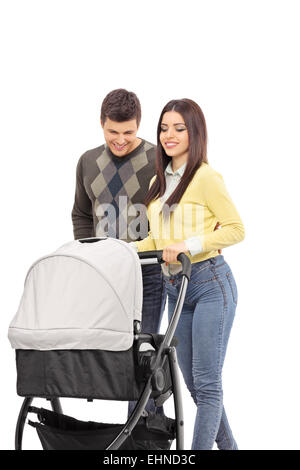 Vertical shot of young parents pushing a baby stroller isolated on white background Stock Photo