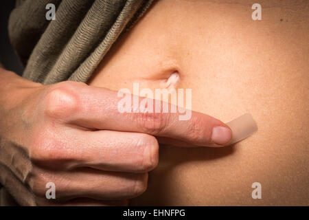 Woman use an oestrogen patch for a Hormone Replacement Therapy (HRT), in order to releive the undesirable effects of menopause. Stock Photo